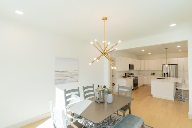 dining room featuring light wood-type flooring, sink, and an inviting chandelier