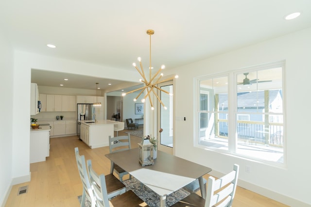 dining space with light hardwood / wood-style flooring and a notable chandelier