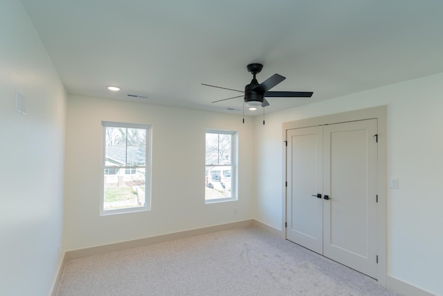 unfurnished bedroom with ceiling fan, light carpet, and a closet