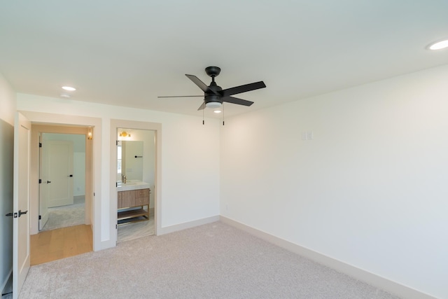 unfurnished bedroom with ceiling fan, light colored carpet, and ensuite bathroom