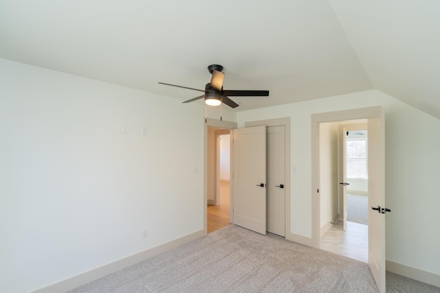 unfurnished bedroom with ceiling fan, a closet, light carpet, and lofted ceiling