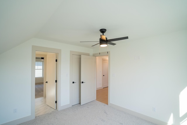 unfurnished bedroom with ceiling fan, light colored carpet, and lofted ceiling