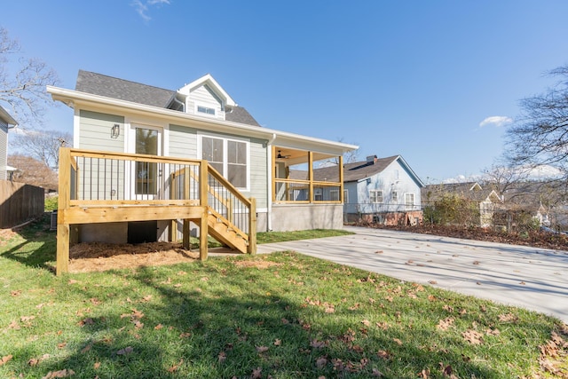 back of house featuring a lawn, a sunroom, a patio area, and a deck