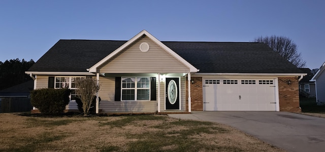 view of front of house featuring brick siding, driveway, a front yard, and a garage