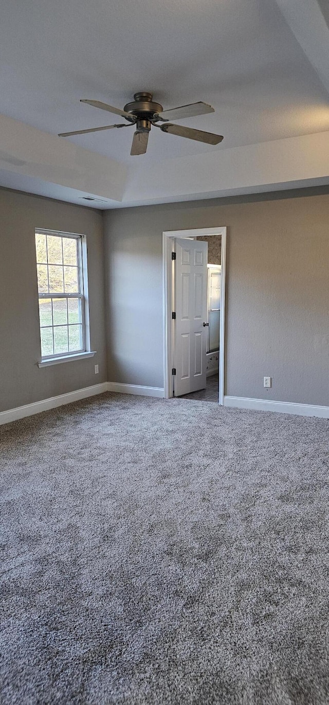 carpeted spare room with a ceiling fan and baseboards