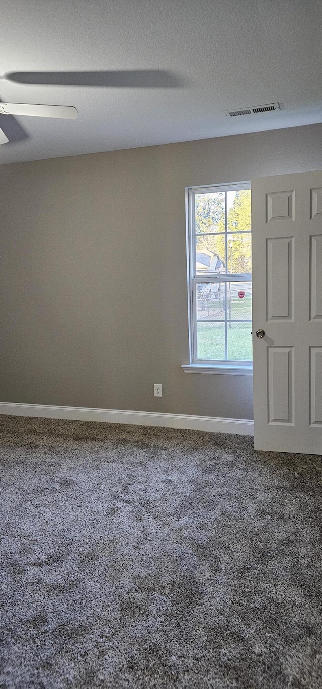 carpeted spare room with visible vents, baseboards, a textured ceiling, and a ceiling fan