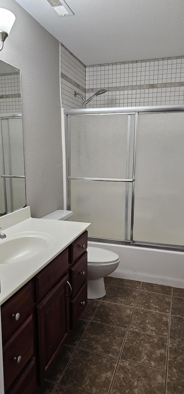 bathroom with vanity, toilet, and combined bath / shower with glass door