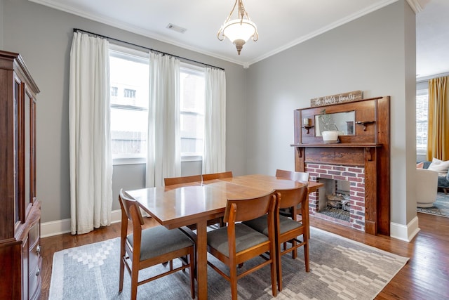 dining space featuring crown molding, a fireplace, and hardwood / wood-style flooring