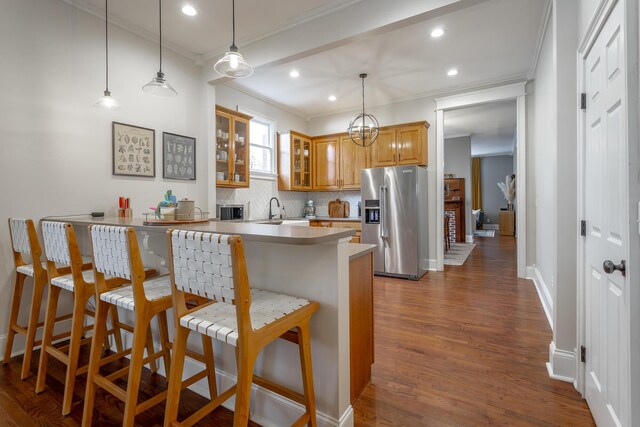 kitchen featuring a kitchen bar, hardwood / wood-style floors, sink, pendant lighting, and stainless steel fridge with ice dispenser