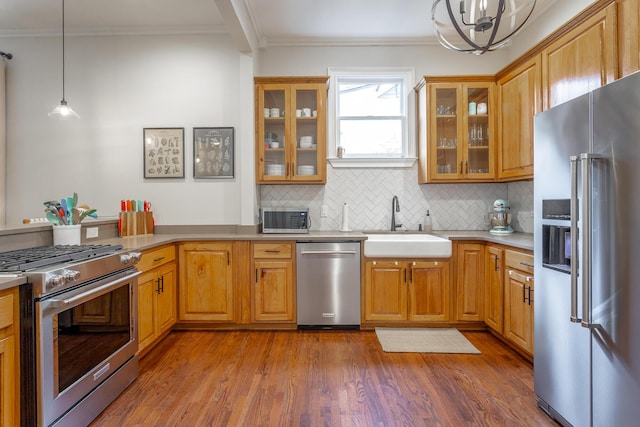 kitchen featuring sink, hanging light fixtures, ornamental molding, tasteful backsplash, and premium appliances