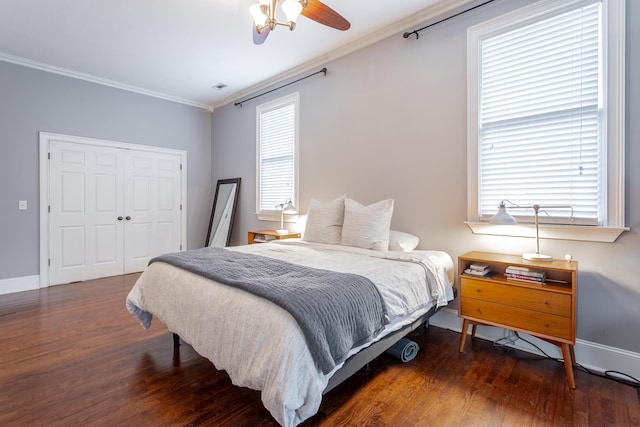 bedroom with dark wood-type flooring, a closet, ceiling fan, and ornamental molding