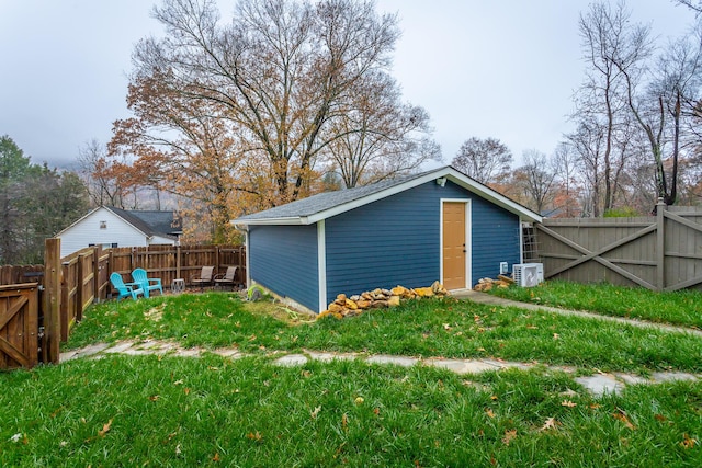 view of outbuilding featuring ac unit, a yard, and a fire pit