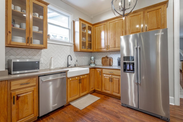 kitchen featuring sink, an inviting chandelier, dark hardwood / wood-style floors, decorative backsplash, and appliances with stainless steel finishes