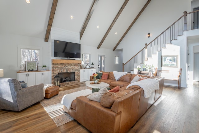 living room with high vaulted ceiling, light wood-type flooring, a fireplace, and beam ceiling