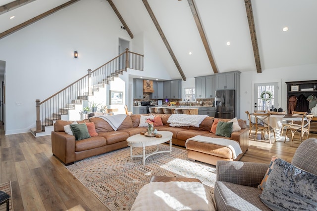 living room featuring beamed ceiling, high vaulted ceiling, and light hardwood / wood-style flooring