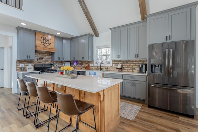 kitchen with a kitchen bar, tasteful backsplash, stainless steel fridge, beam ceiling, and stove