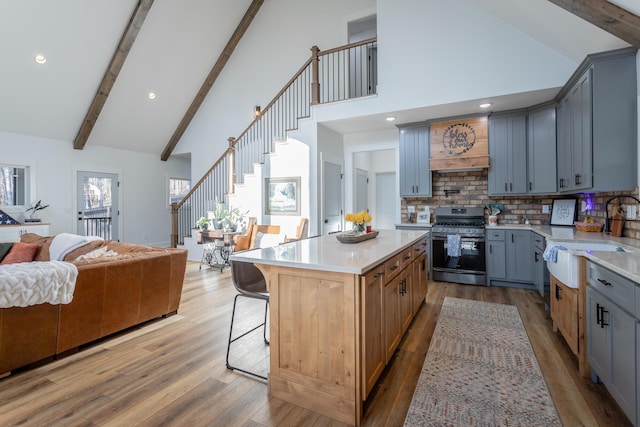 kitchen with sink, tasteful backsplash, high vaulted ceiling, stainless steel range with gas stovetop, and custom range hood