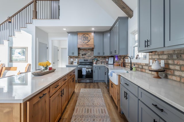 kitchen with premium range hood, tasteful backsplash, sink, stainless steel gas range oven, and beam ceiling