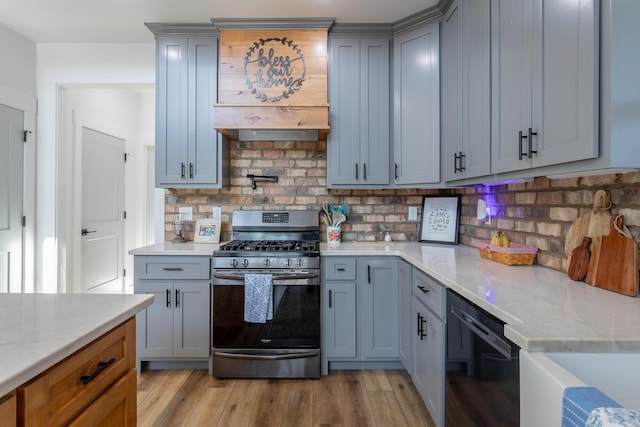 kitchen with light stone counters, backsplash, and stainless steel range with gas cooktop