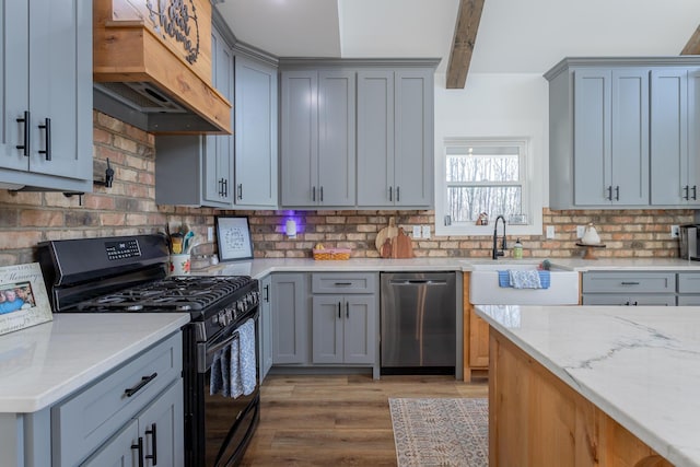 kitchen featuring premium range hood, black gas stove, stainless steel dishwasher, light stone countertops, and beam ceiling