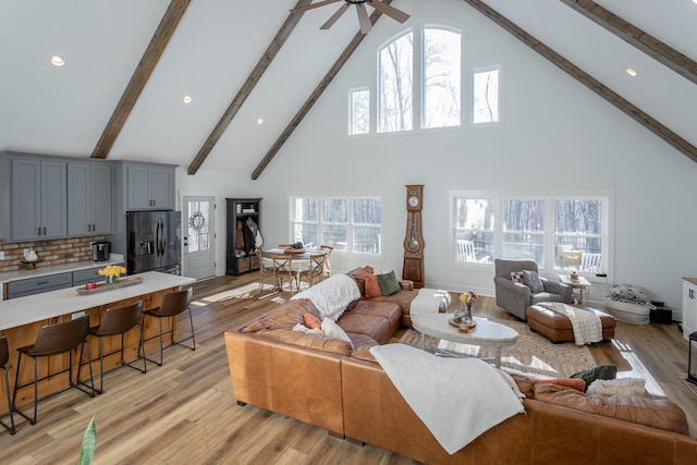 living room featuring beam ceiling, plenty of natural light, high vaulted ceiling, and light hardwood / wood-style floors