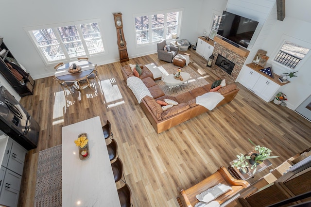 living room with a brick fireplace, hardwood / wood-style flooring, and a towering ceiling