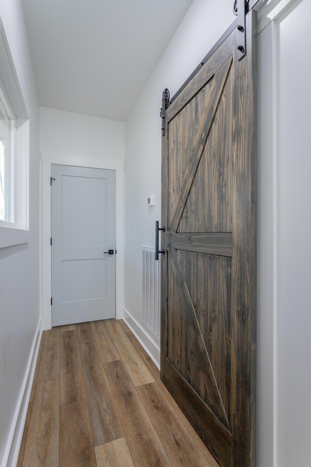 corridor with a barn door and light hardwood / wood-style flooring