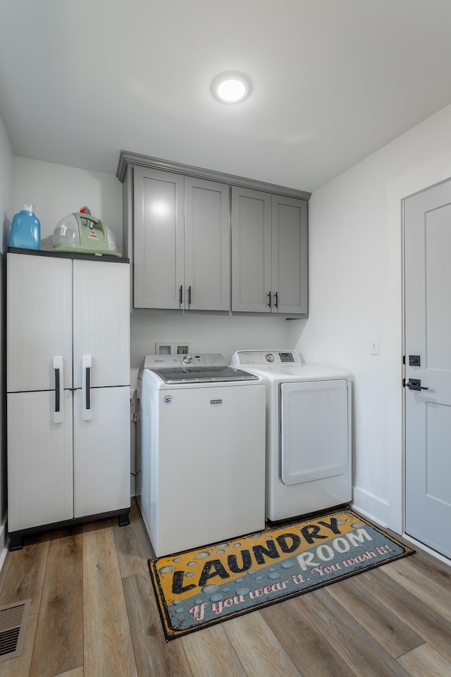 clothes washing area featuring cabinets, independent washer and dryer, and light hardwood / wood-style floors