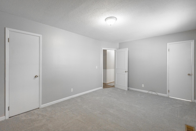 unfurnished bedroom with a textured ceiling and light carpet