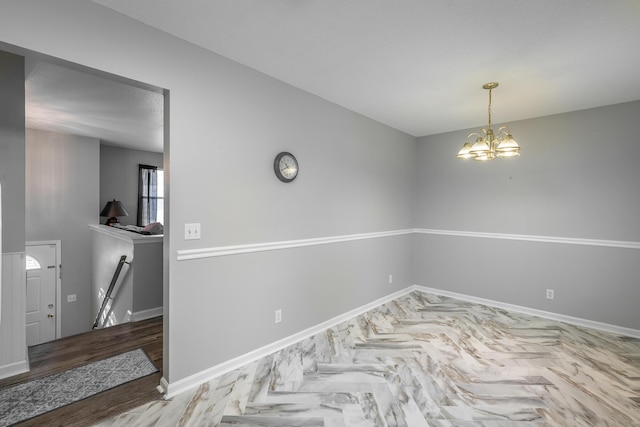 spare room featuring hardwood / wood-style floors and a notable chandelier