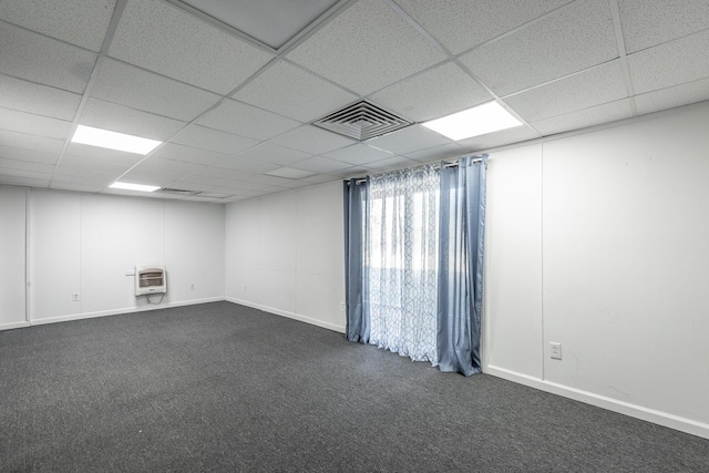 spare room featuring a paneled ceiling, heating unit, and dark carpet