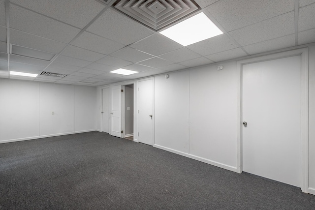 basement featuring a paneled ceiling and dark carpet