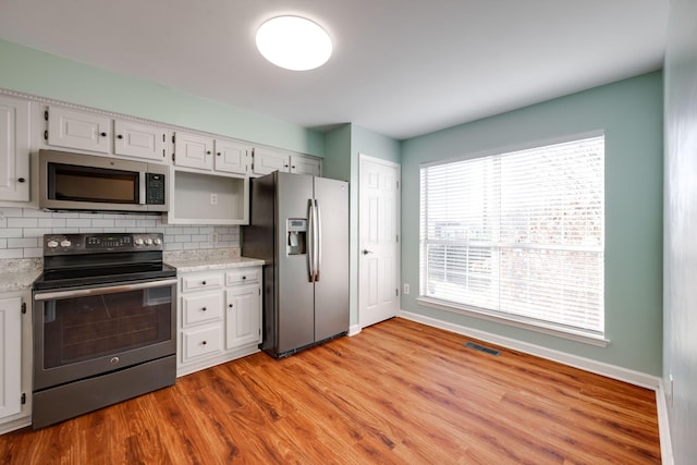 kitchen featuring decorative backsplash, white cabinetry, stainless steel appliances, and light hardwood / wood-style flooring