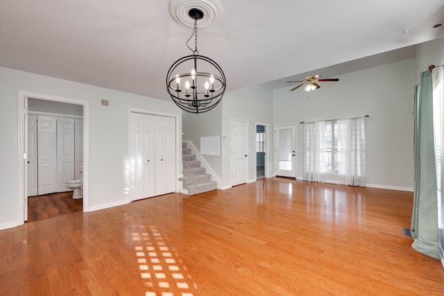 unfurnished living room with ceiling fan with notable chandelier, hardwood / wood-style flooring, and a wealth of natural light