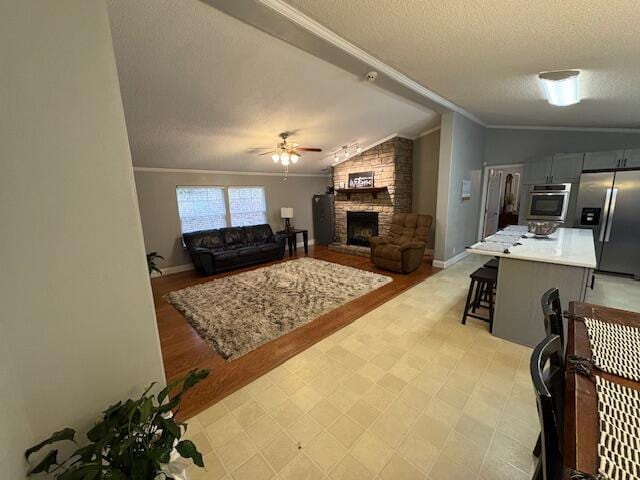 living room with lofted ceiling, crown molding, ceiling fan, a textured ceiling, and a fireplace