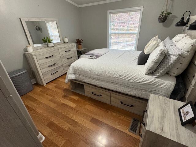 bedroom featuring wood-type flooring and ornamental molding