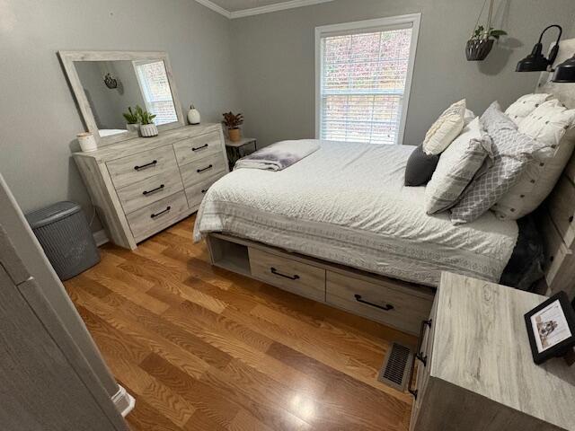 bedroom with crown molding and wood-type flooring