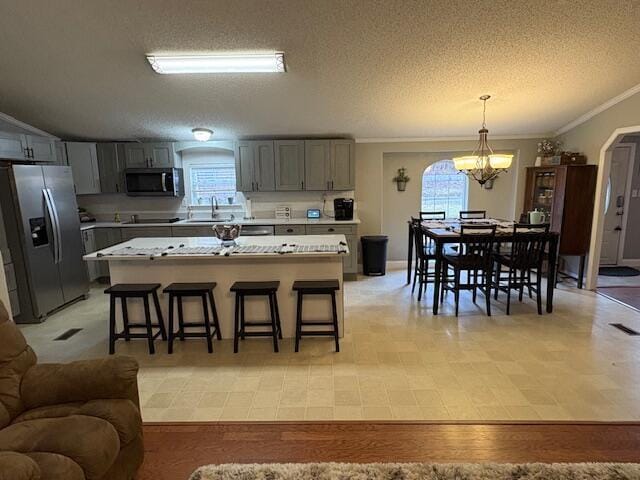 kitchen featuring a textured ceiling, stainless steel appliances, sink, a notable chandelier, and hanging light fixtures