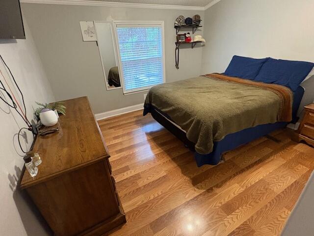 bedroom with crown molding and hardwood / wood-style floors