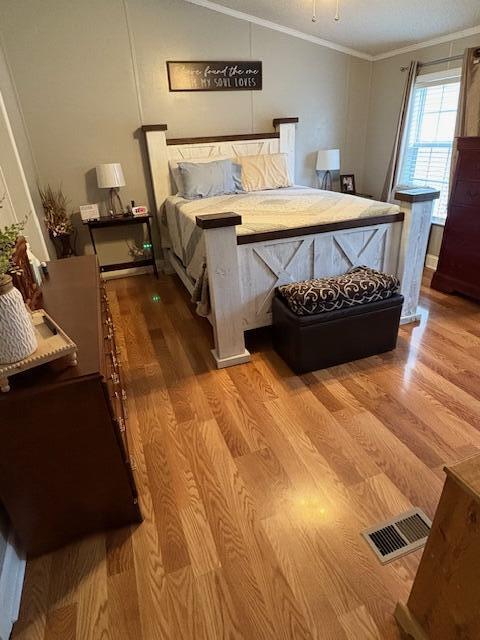 bedroom featuring light hardwood / wood-style floors and crown molding