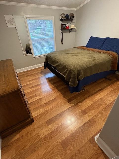 bedroom with crown molding and wood-type flooring