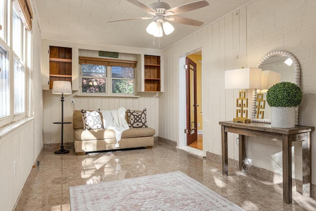 living area featuring wood walls and ceiling fan