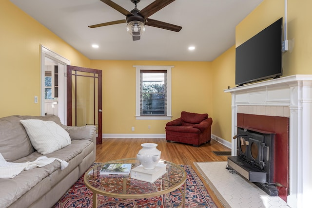 living room featuring a wood stove, ceiling fan, and light hardwood / wood-style floors