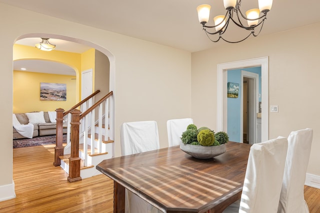 dining room with light wood-type flooring and an inviting chandelier