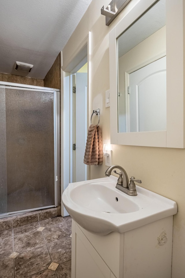 bathroom featuring vanity, a textured ceiling, and walk in shower