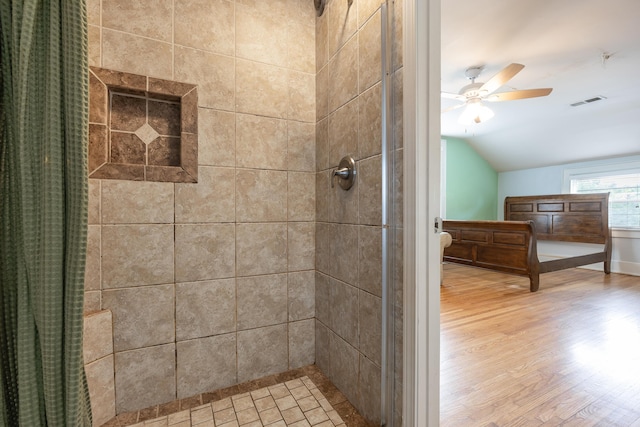 bathroom featuring a tile shower, ceiling fan, wood-type flooring, and lofted ceiling