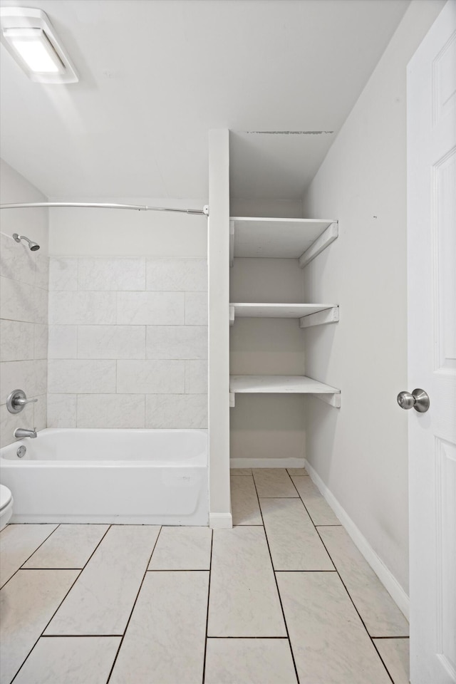 bathroom with tiled shower / bath, toilet, and tile patterned flooring