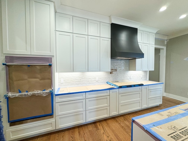 kitchen featuring white cabinets, gas stovetop, custom range hood, and backsplash