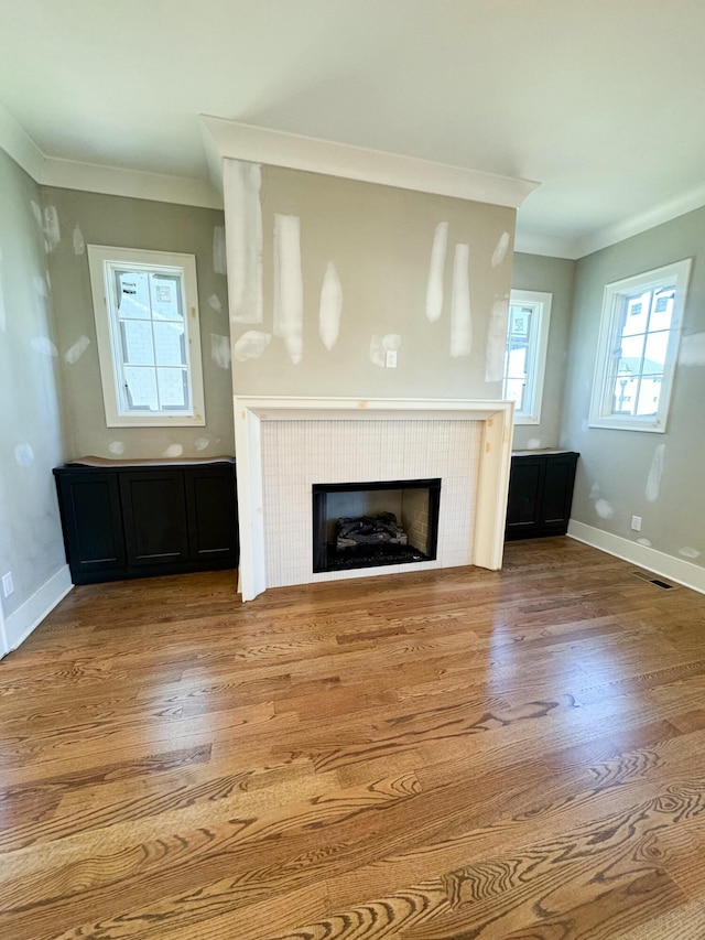 unfurnished living room featuring hardwood / wood-style flooring and ornamental molding