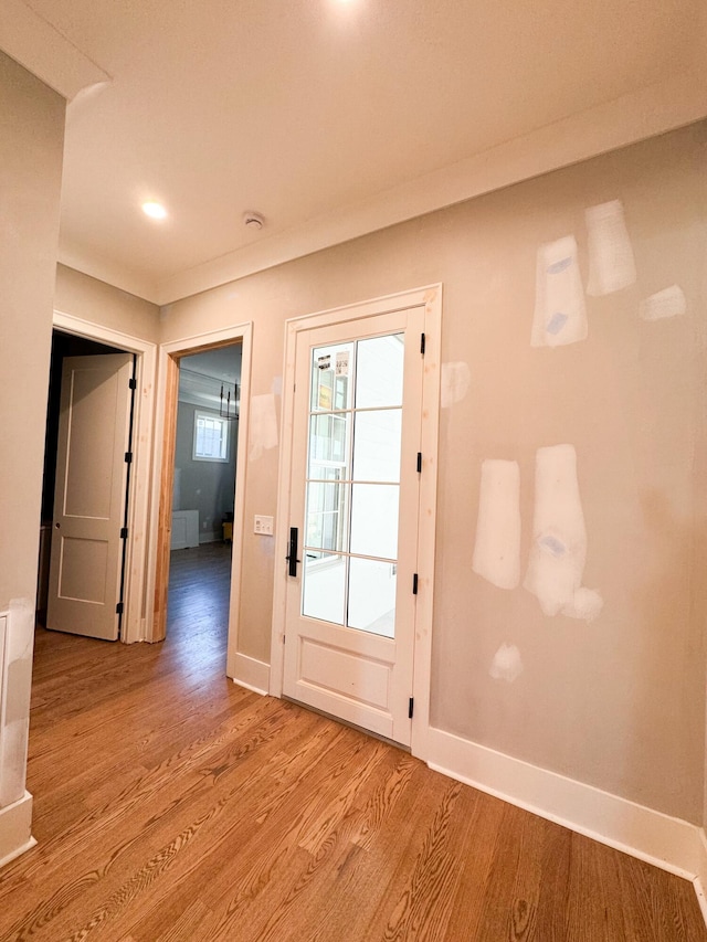 doorway with light hardwood / wood-style floors and ornamental molding